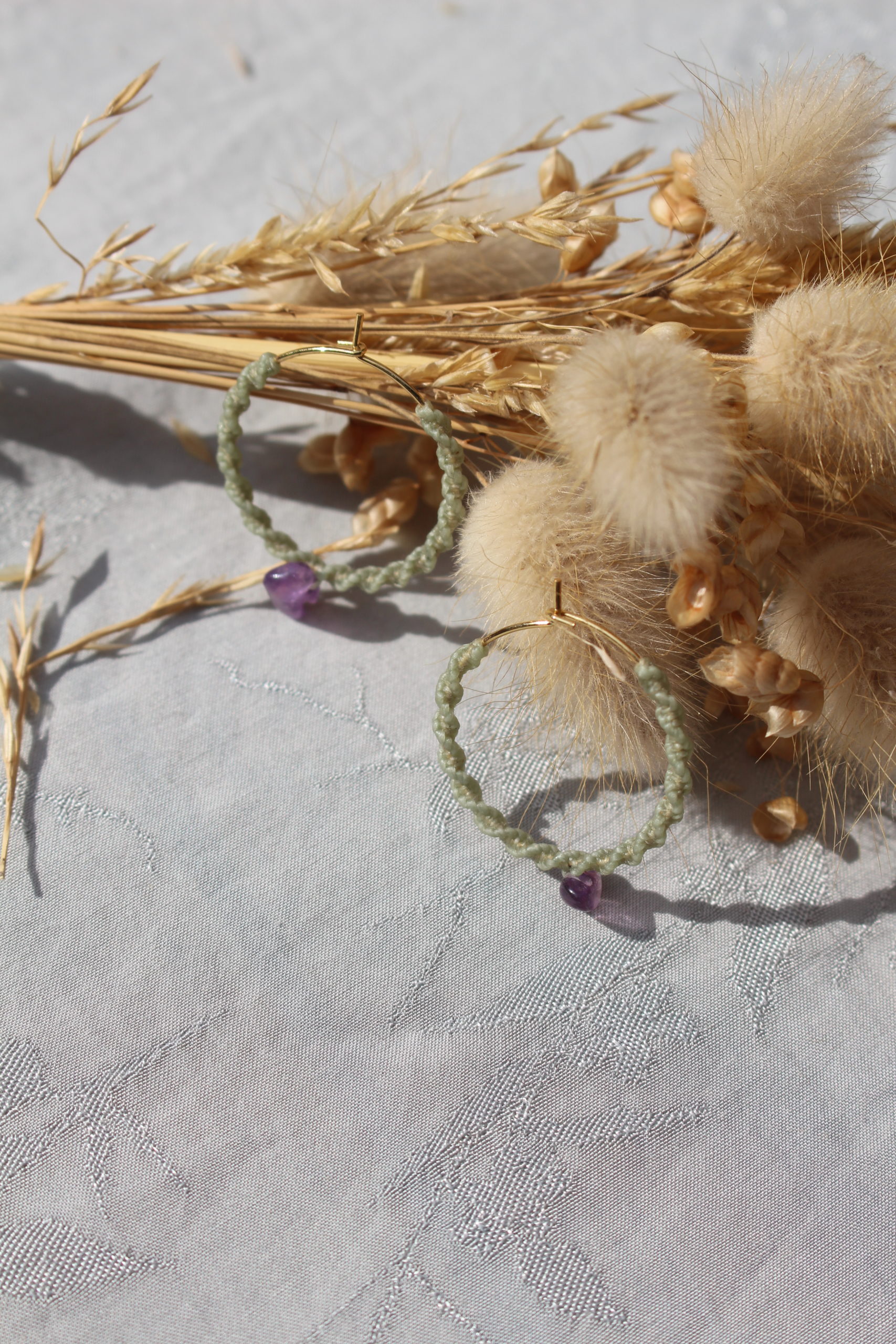 Ces créoles allient à la fois un style bohème et moderne. Le macramé apporte une touche artisanale et naturelle, tandis que la forme circulaire et la pierre en semi-précieuse