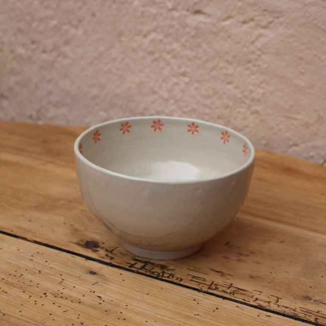 Couleur : Le bol est principalement de couleur beige clair, offrant une base neutre et apaisante. Motif : Le bord intérieur du bol est orné d'un motif délicat de petites fleurs d'un rose corail vif, créant un contraste agréable avec la couleur de fond beige.