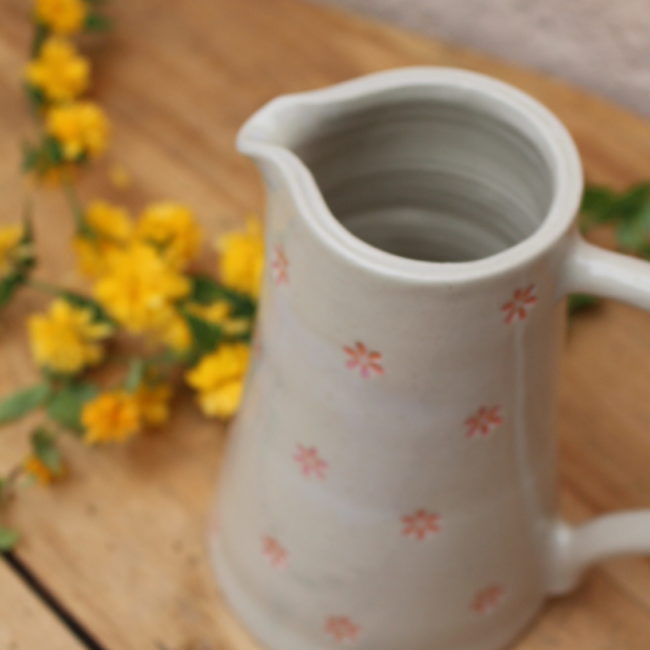 Couleur : Le pichet est principalement de couleur beige clair, offrant une base neutre et apaisante. Motif : La surface du pichet est ornée d'un motif délicat de petites fleurs d'un rose corail vif, réparties de manière aléatoire sur toute sa surface. Ces fleurs ajoutent une touche de fantaisie et de gaieté.