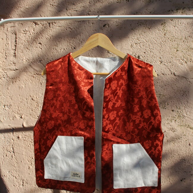 Ce gilet rouge sans manches fabrique en France, est une pièce unique et originale qui allie confort et style. Sa couleur rouge, ses motifs et sa coupe ample en font un vêtement tendance, intemporel et mixte. Il est parfait pour ceux qui souhaitent ajouter une touche unique à leur garde-robe. Face un : Tissus rouge arabesques satinées, poches tissus blanc motifs ton sur ton Face deux : Tissus blanc motifs ton sur ton, poches rouges arabesques satinées Nos idées : Quotidien: Il peut être porté au quotidien pour ajouter une touche de couleur et de style à une tenue décontractée.
