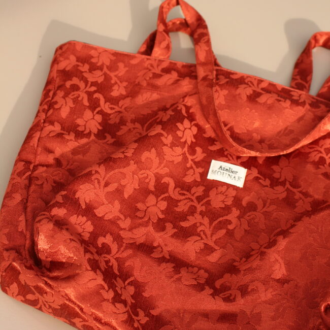 Ce sac cabas rouge est un incontournable pour un look décontracté. Arabesque rouge sur fond rouge. Offrant une grande capacité de rangement.